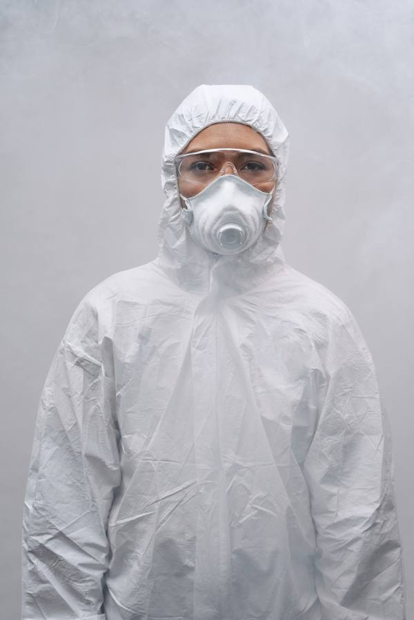 Worker wearing a hooded white disposable coverall, respirator and safety glasses