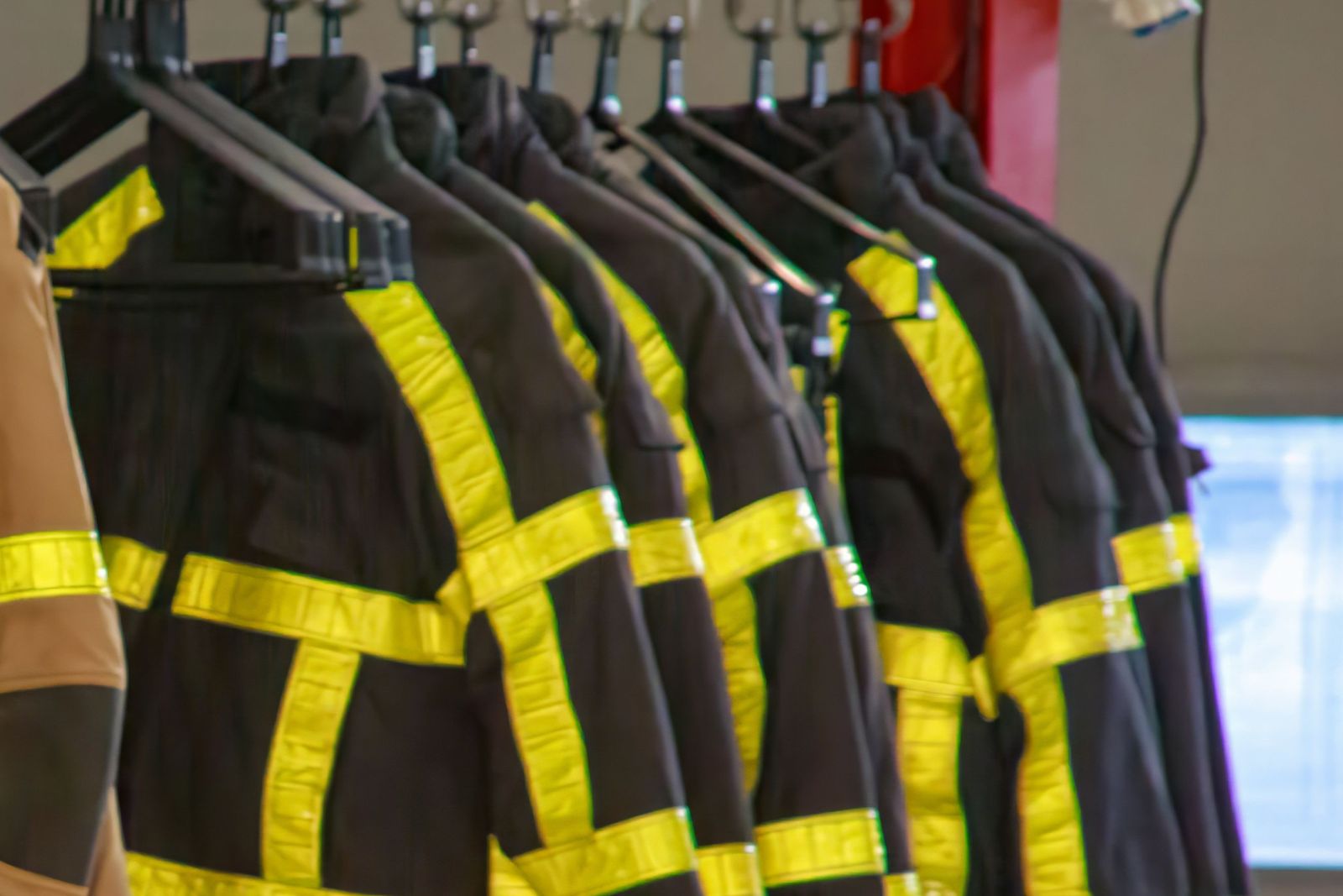 Firefighter turnout jackets with reflective trim hanging in a fire station