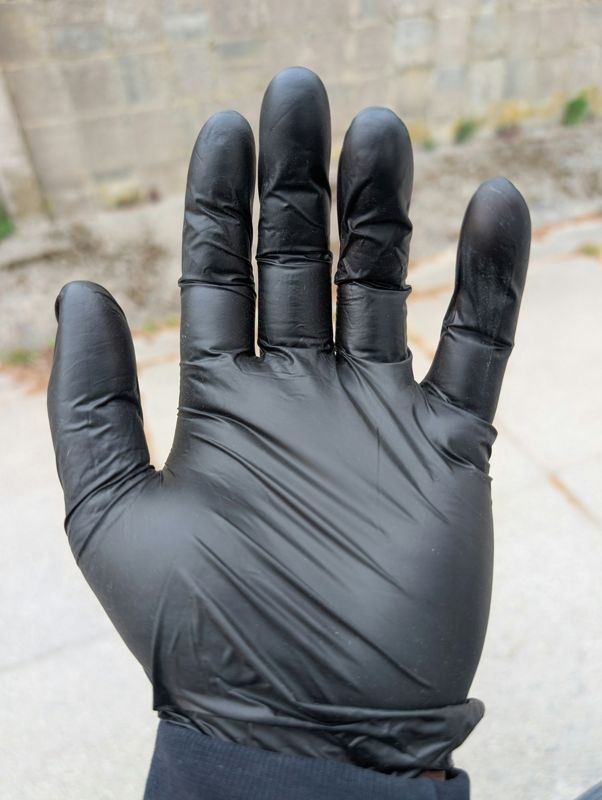 Hand wearing a black nitrile disposable glove