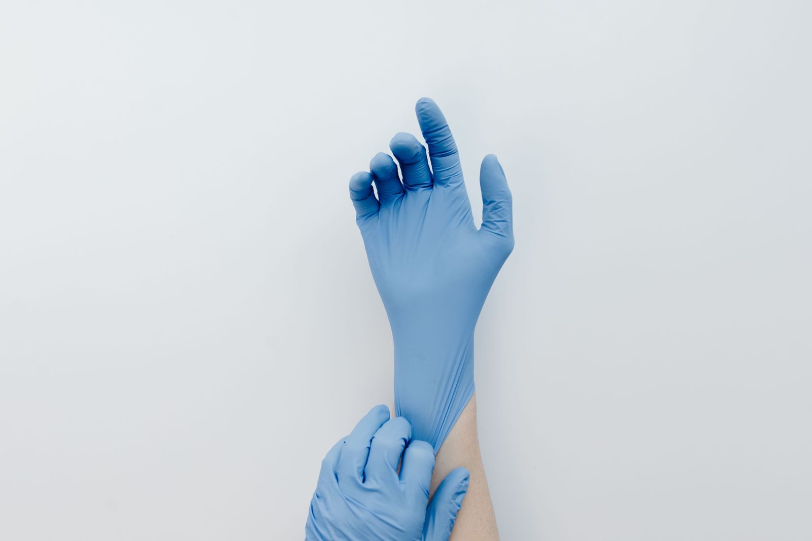 Pulling a blue nitrile glove on at the cuff