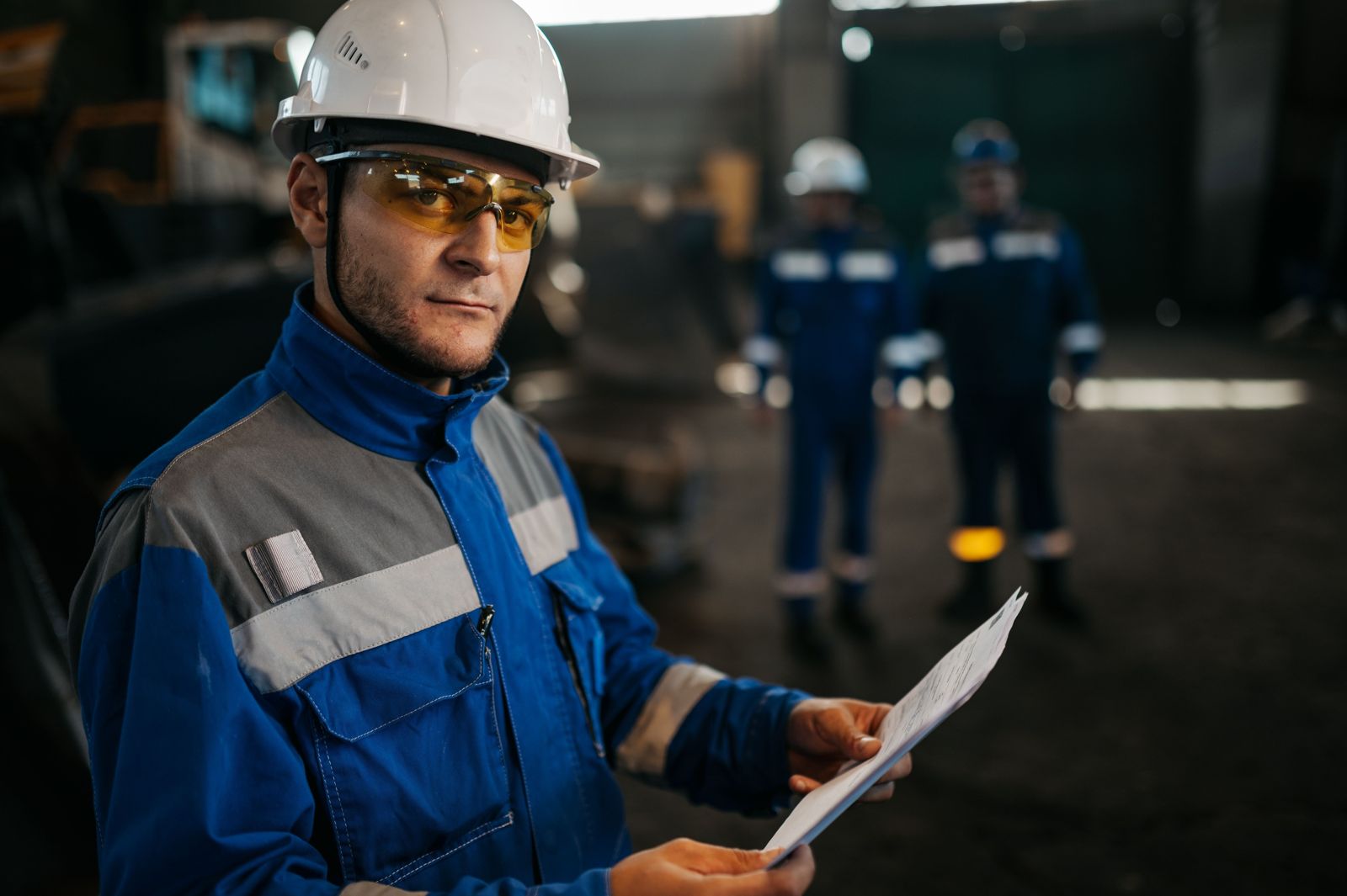 Industrial worker wearing amber safety glasses and a white hard hat