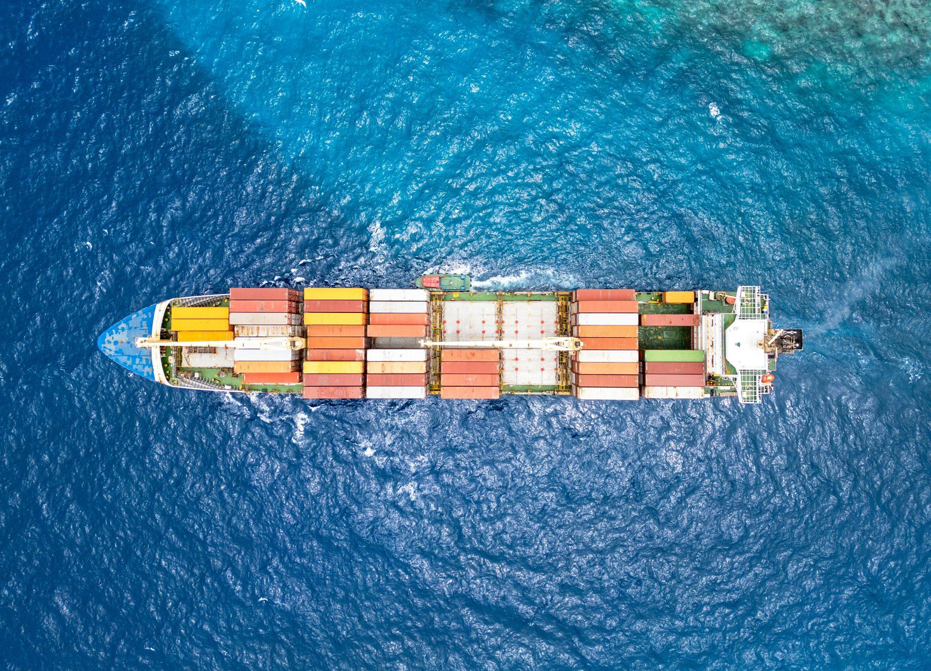 Aerial view of a loaded container ship crossing deep blue open ocean