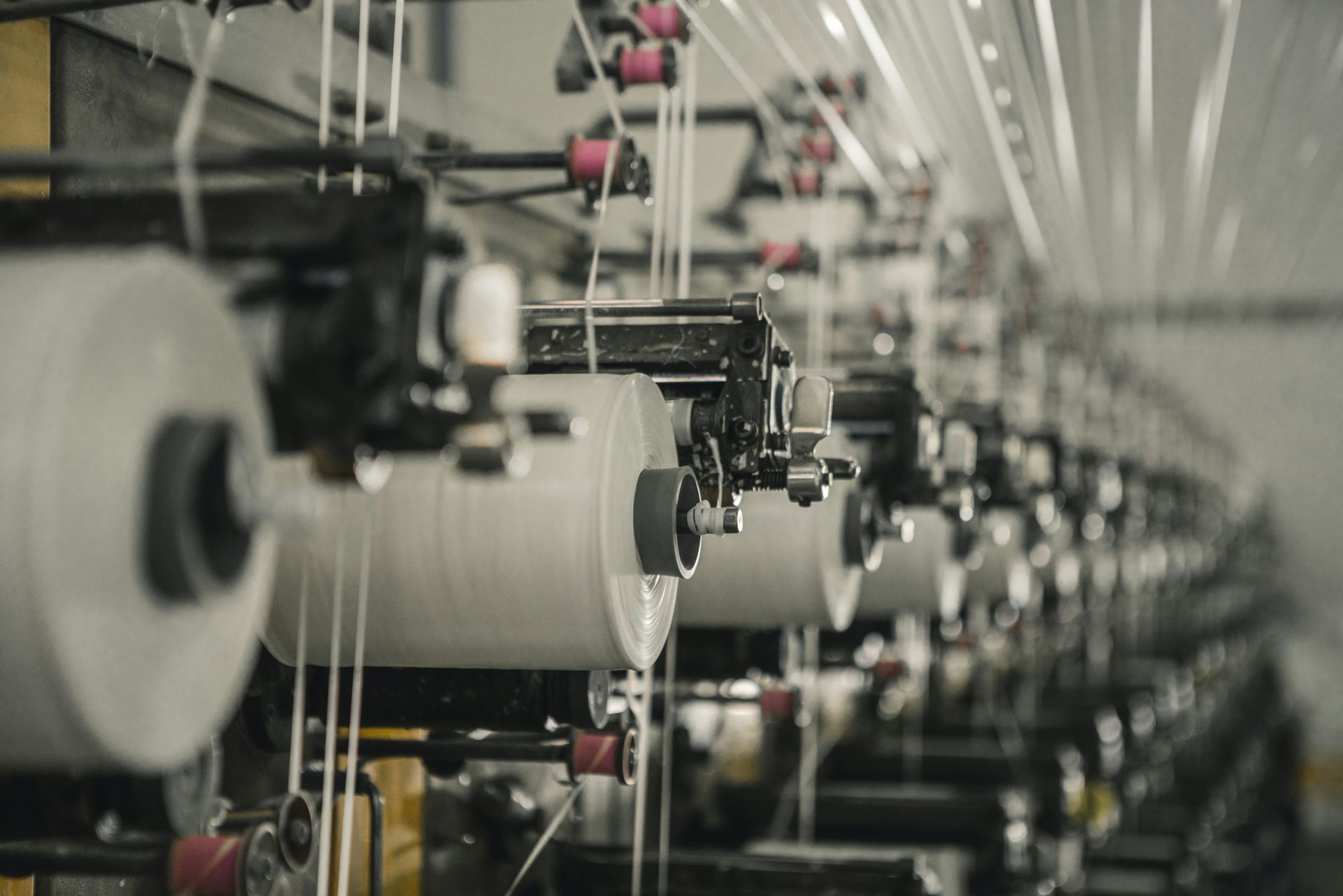Rows of white thread spools running on industrial textile machinery